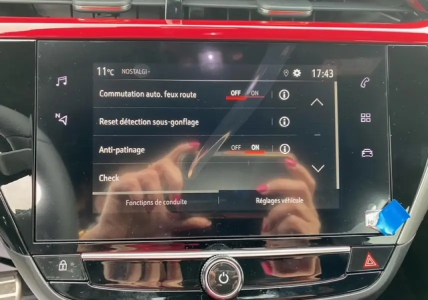 Écran tactile 7 pouces de l’Opel Corsa GS Line 2022 affichant les réglages de conduite, avec reflets de mains.
