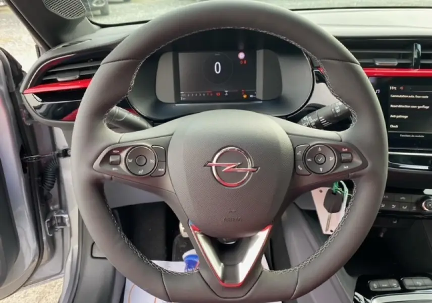 Vue intérieure centrée sur le volant cuir de l’Opel Corsa gris magnetic avec tableau de bord digital et touches multifonctions.