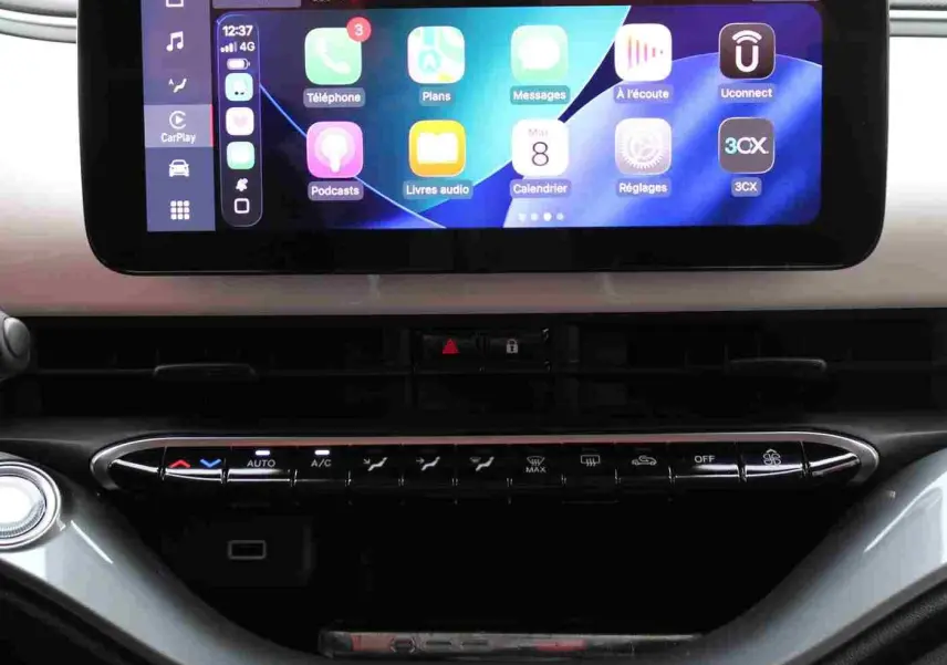 Écran tactile central affichant l'interface CarPlay sur le tableau de bord de la Fiat 500 électrique blanche.