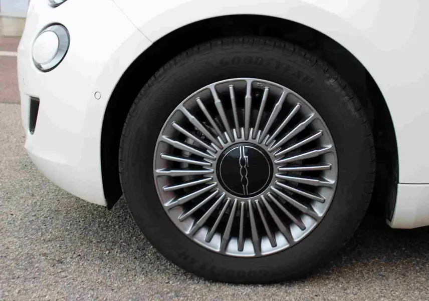 Gros plan sur la jante avant droite argentée au design rayonné d'une FIAT 500 électrique blanche de 2023.