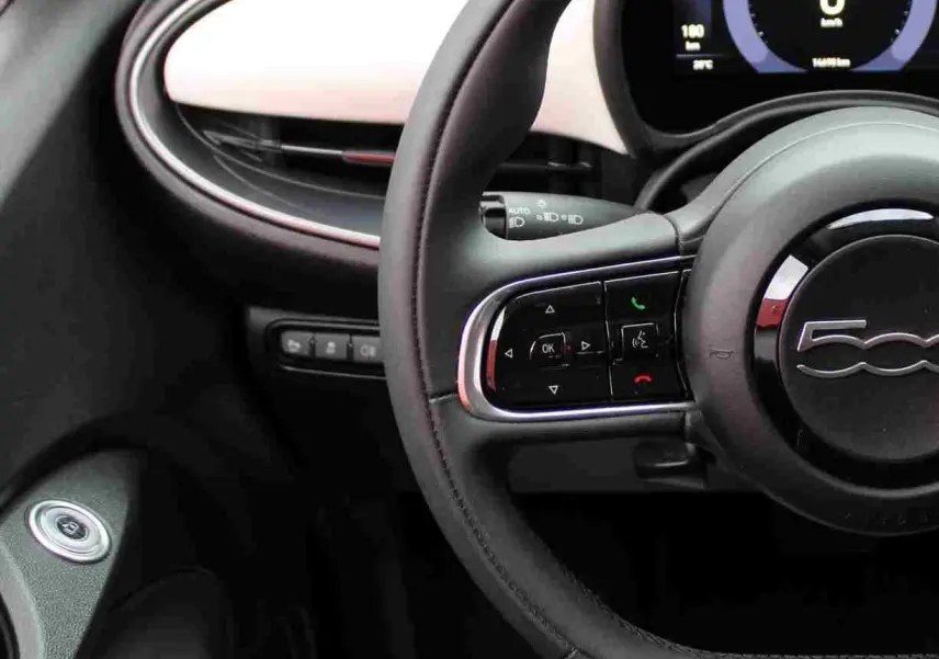 Vue rapprochée du volant noir et du tableau de bord blanc de la Fiat 500 électrique 2023 avec affichage numérique.