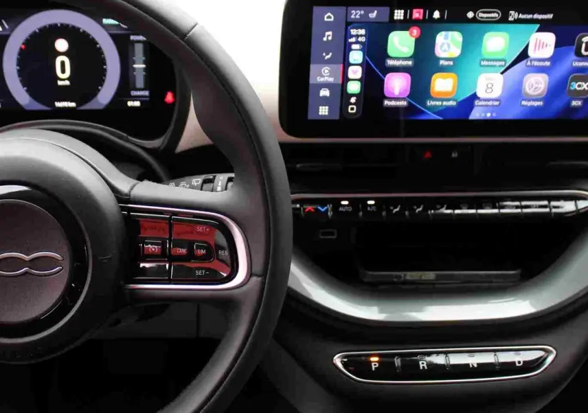 Vue intérieure du tableau de bord de la Fiat 500 électrique 2023, avec écran tactile CarPlay et volant multifonction noir.