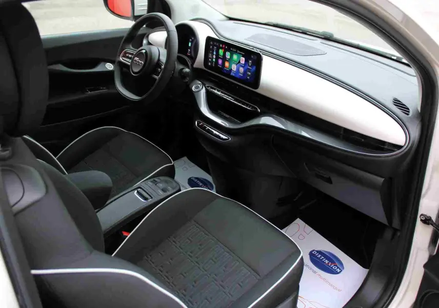 Intérieur avant droit de la Fiat 500 électrique blanche 2023, avec tableau de bord moderne et écran tactile central.