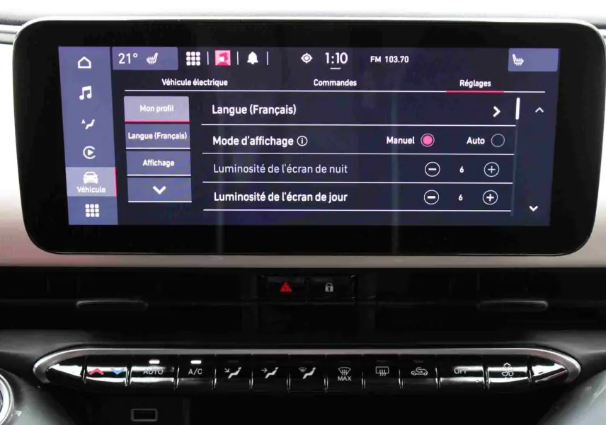 Écran tactile central de la Fiat 500 électrique 2023 montrant les réglages de langue et luminosité, intérieur noir.