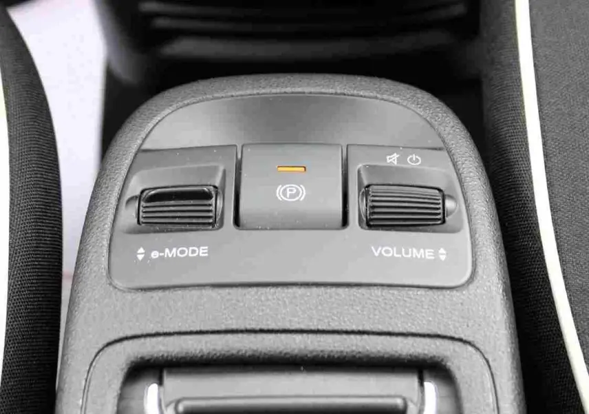 Gros plan sur la console centrale de la Fiat 500 électrique blanche, avec commandes e-Mode, frein à main électronique et réglage du volume.