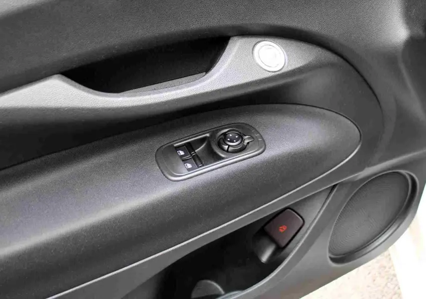 Gros plan sur la porte côté conducteur de la FIAT 500 électrique blanche, montrant les commandes de vitres et le haut-parleur intégré.