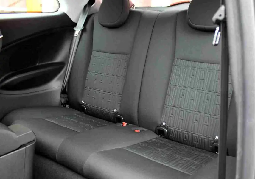 Vue intérieure de la banquette arrière noire de la Fiat 500 électrique 2023 avec motifs FIAT embossés sur les sièges.