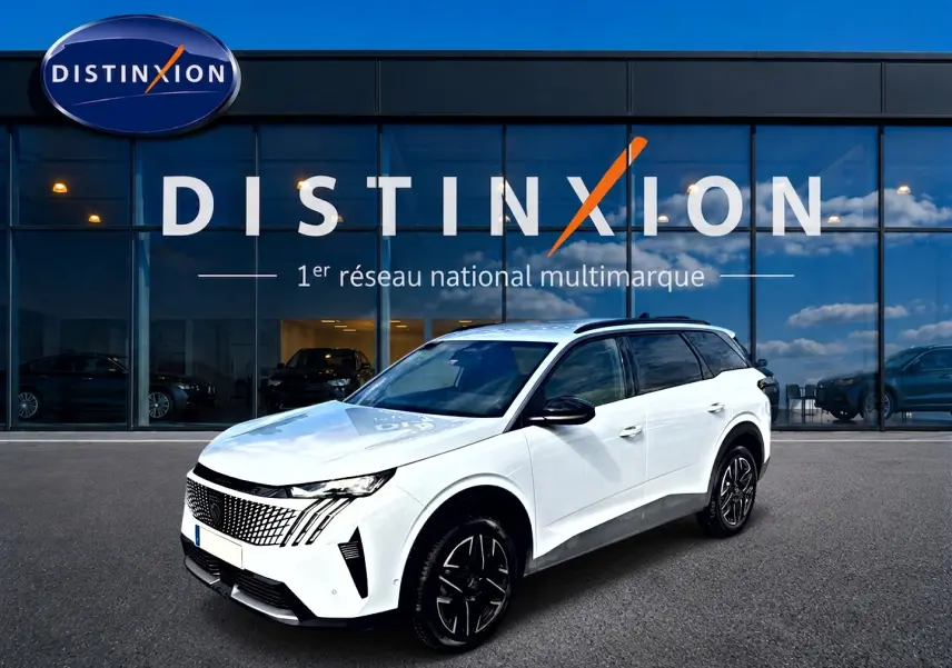 Peugeot 5008 Hybrid blanc en 3/4 avant droit, avec jantes noires et toit noir, devant une vitrine Distinxion.