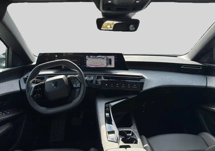 Vue intérieure avant du Peugeot 5008 blanc 2025, mettant en valeur le tableau de bord numérique et le volant cuir multifonction.