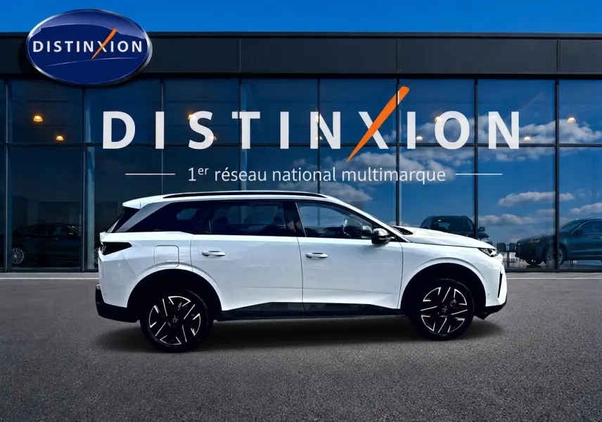 Peugeot 5008 Hybrid 145 allure blanc vue de profil côté gauche devant une vitrine avec logo Distinxion.