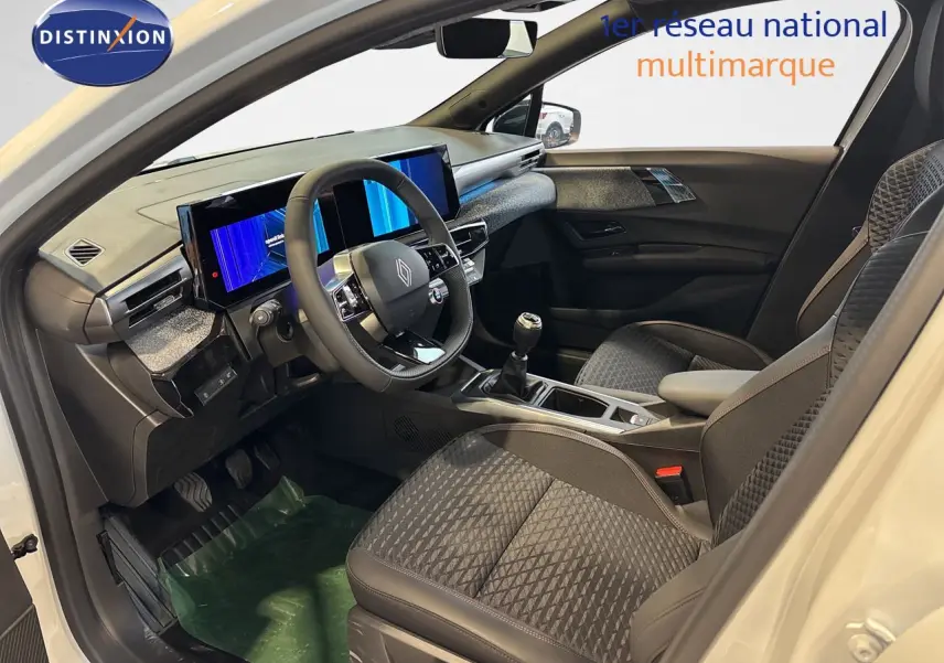 Vue intérieure côté conducteur de la Renault Clio VI TCe 115ch Techno blanche, volant cuir et écran digital double.