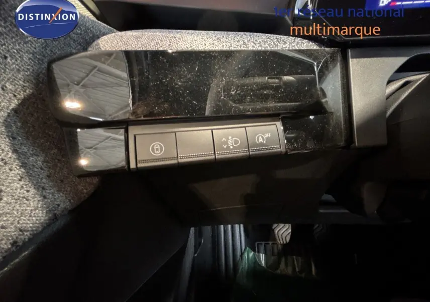 Détail intérieur montrant les commandes de réglage des phares et fonctions assistées sur une Renault Clio blanche.