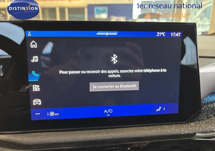 Écran tactile central de la Renault Clio VI blanc glacier, affichant la connexion Bluetooth et la climatisation à 21°C.