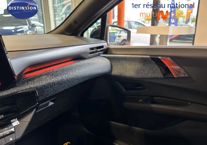 Vue intérieure côté passager de la Renault Clio VI TCe 115ch Techno 2026, ambiance noire avec éclairage d'ambiance rouge.