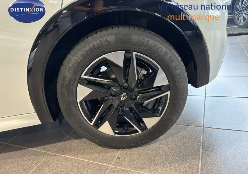 Gros plan sur la roue avant gauche de la Renault Clio blanc glacier avec jante alliage noir et argent.