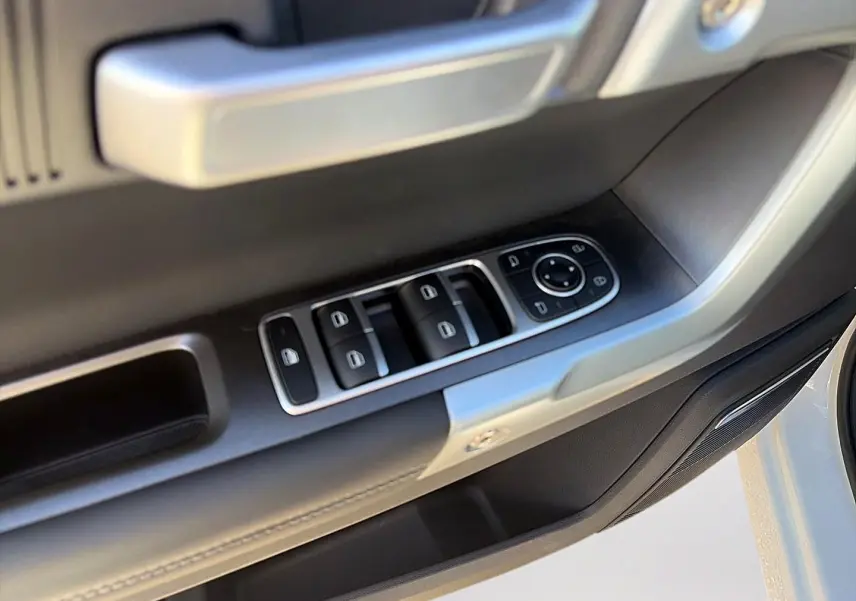 Gros plan sur la commande des vitres et rétroviseurs côté gauche d'une porte blanc kaki du JAECOO J7 2026.