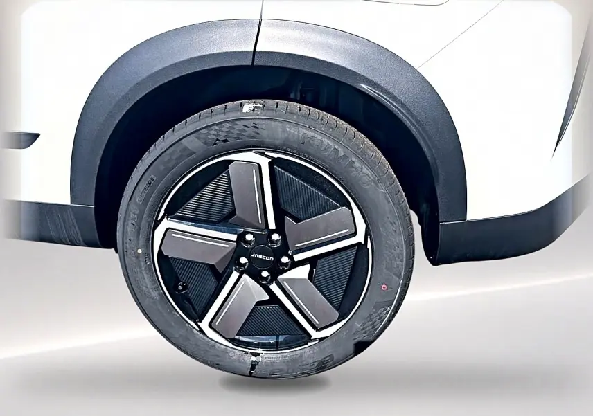 Gros plan sur la roue arrière droite du JAECOO J7 blanc kaki avec jante alu noire et argentée au design moderne.