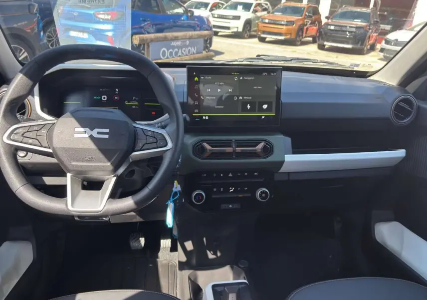 Vue intérieure du tableau de bord du Dacia Spring électrique bleu ardoise, avec écran tactile central et volant multifonction.