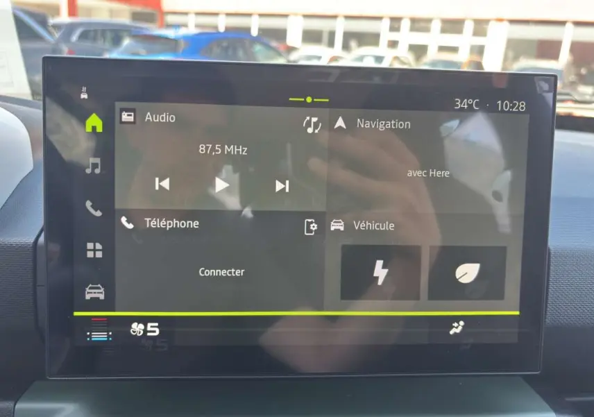 Écran tactile central du tableau de bord du Dacia Spring 2026 affichant radio, navigation et options connectées.