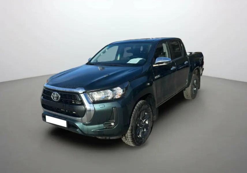 Toyota Hilux 2025 vert métal en 3/4 avant droit, pick-up 4x4 robuste avec jantes noires et calandre chromée.