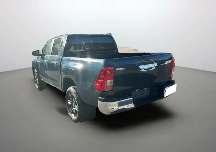 Toyota Hilux 2025 vert métal en 3/4 arrière droit, mettant en valeur sa benne et ses feux arrière rouges.