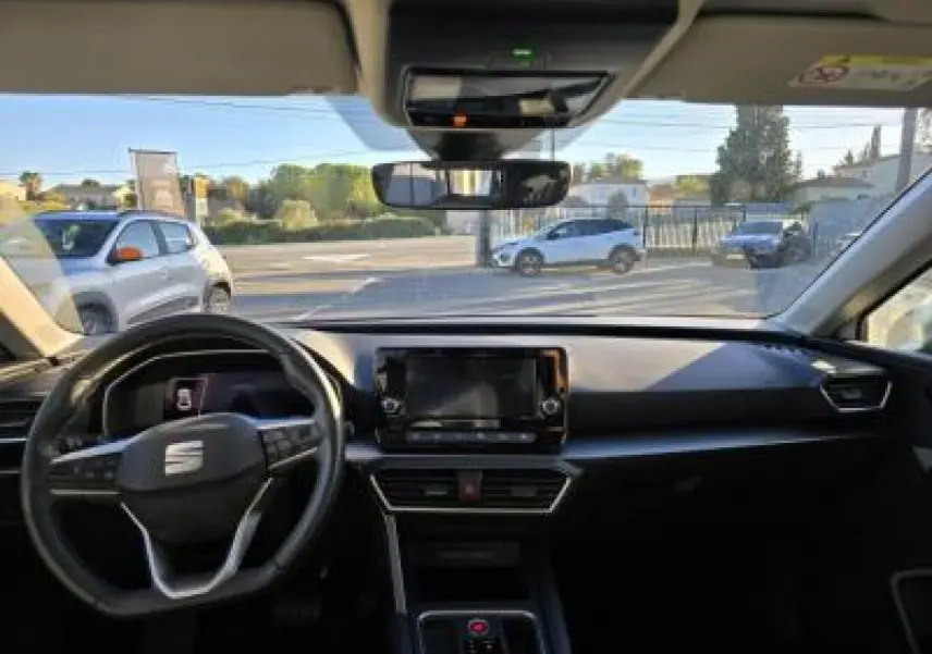 Vue intérieure avant du tableau de bord et volant cuir multifonction de la SEAT LEON blanche 2024 avec écran tactile central.