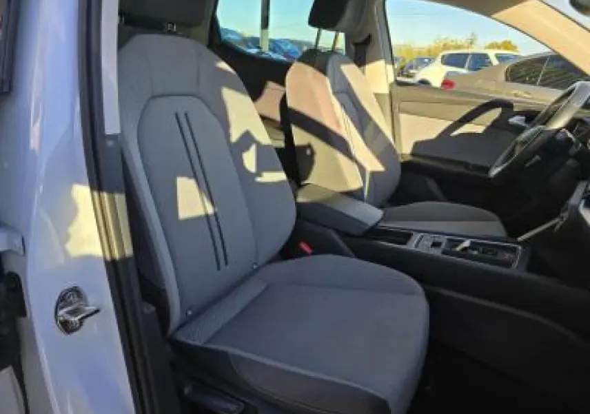 Vue intérieure côté conducteur de la SEAT LEON blanche 2024, sièges tissu gris et console centrale moderne.