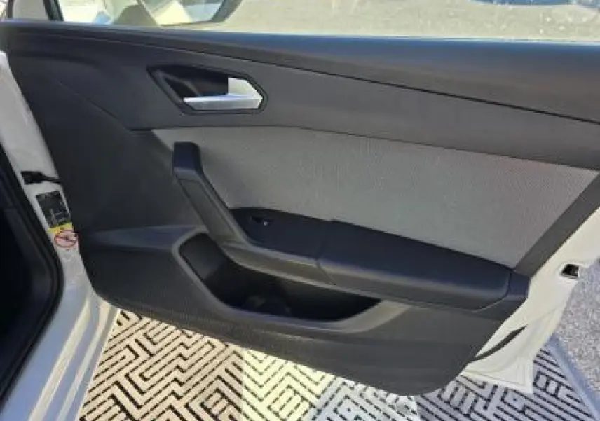 Porte avant gauche ouverte d'une SEAT LEON blanche, montrant le panneau intérieur noir et gris avec poignée argentée.