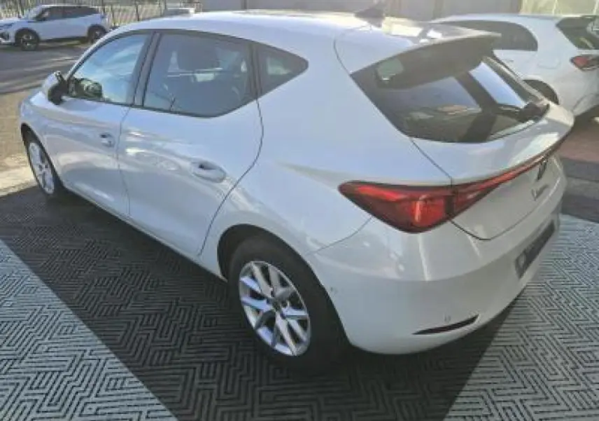 Vue 3/4 arrière droite d'une SEAT Leon blanche 2024 avec jantes alliage et vitres teintées.