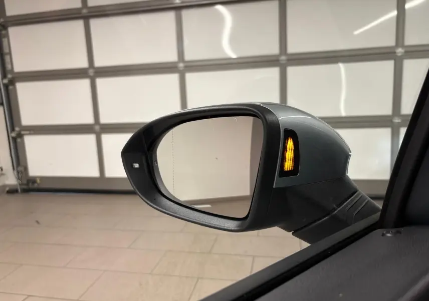 Rétroviseur extérieur côté gauche de la Volkswagen Golf 1.5 TSI argent Dolomite avec clignotant allumé.