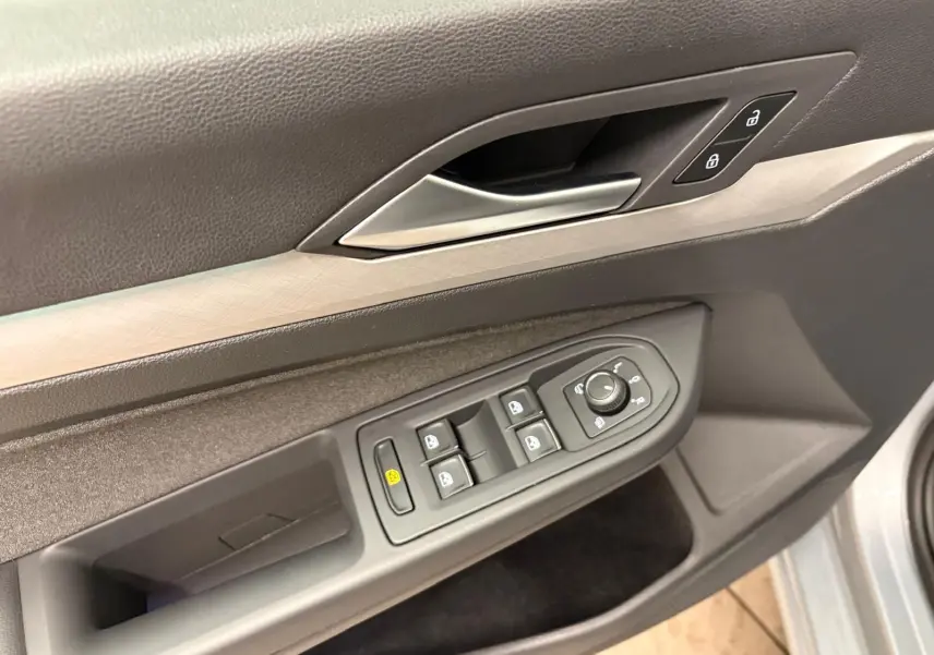 Gros plan sur la commande des vitres et des rétroviseurs côté conducteur de la Volkswagen Golf 1.5 TSI 2025 argent Dolomite.