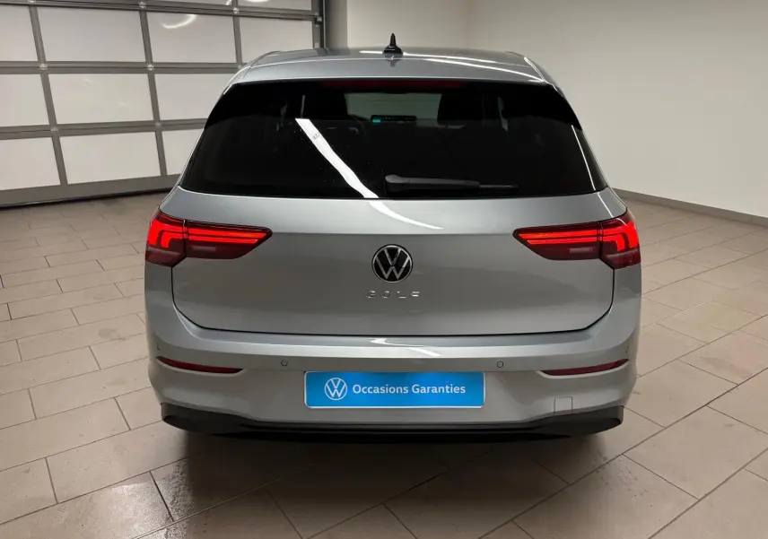 Vue arrière d'une Volkswagen Golf 1.5 TSI 116 BVM6 VW Edition en argent Dolomite avec feux LED allumés dans un garage.