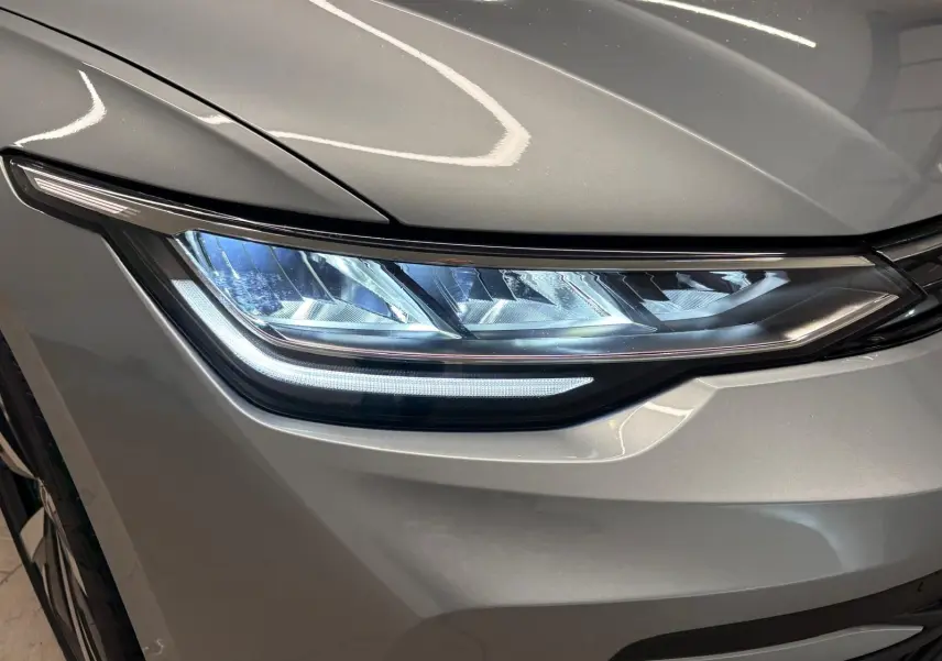 Gros plan sur le phare avant droit d'une Volkswagen Golf 1.5 TSI 2025 en Argent Dolomite métallisé.