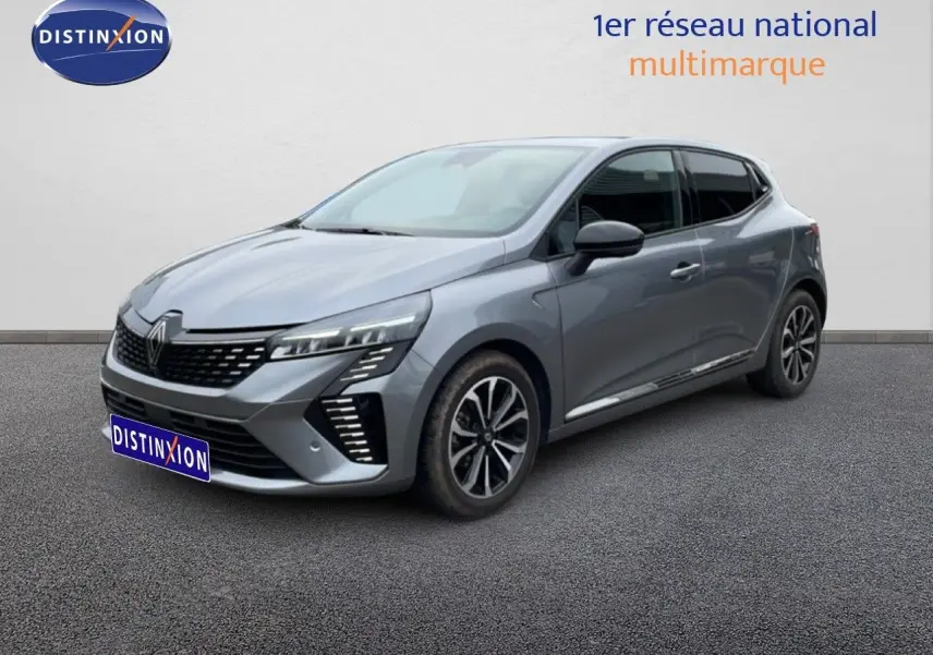 Renault Clio 2025 gris schiste métal en 3/4 avant droit, avec calandre noire et feux LED distinctifs.