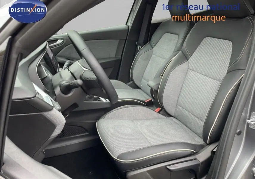 Vue intérieure côté conducteur de la Renault Clio 2025 gris schiste métal, sièges tissu gris avec surpiqûres contrastées.