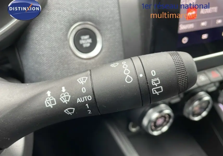 Gros plan sur la commande d’essuie-glace de la Renault Clio gris schiste, avec bouton start et console en arrière-plan flou.