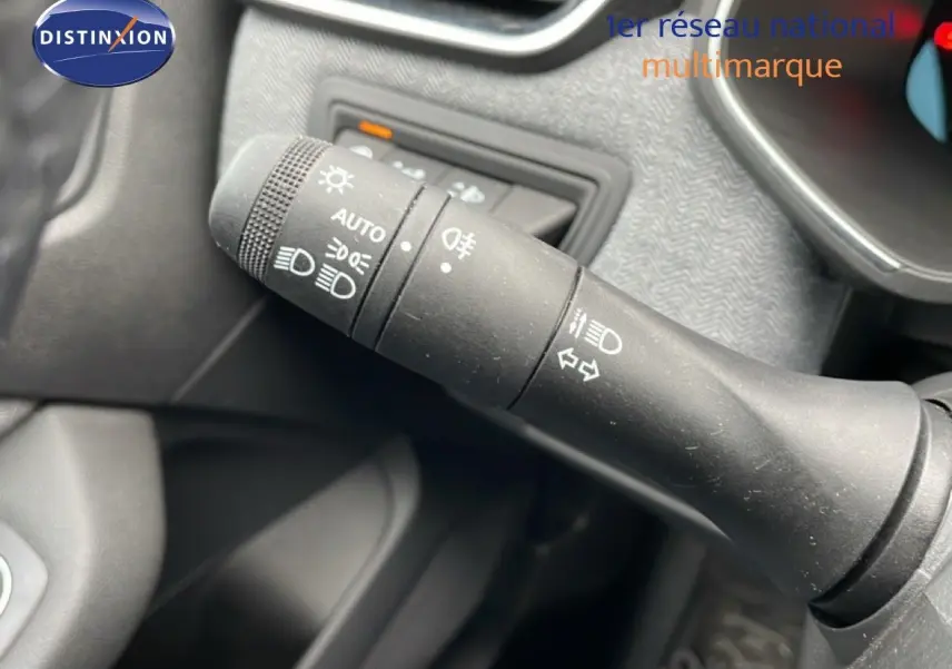 Gros plan sur la commande des feux et clignotants à gauche du volant dans l'habitacle d'une Renault Clio gris schiste.