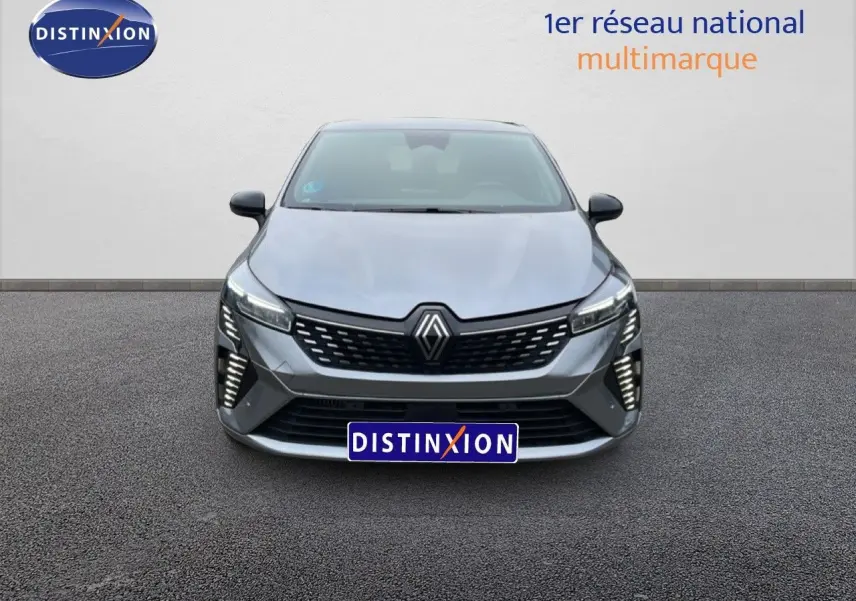Vue de face de la Renault Clio 2025 gris schiste métal avec calandre noire et feux LED verticaux allumés.