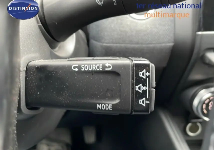 Gros plan sur la commande au volant gauche de la Renault Clio gris schiste, avec boutons source et mode visibles.