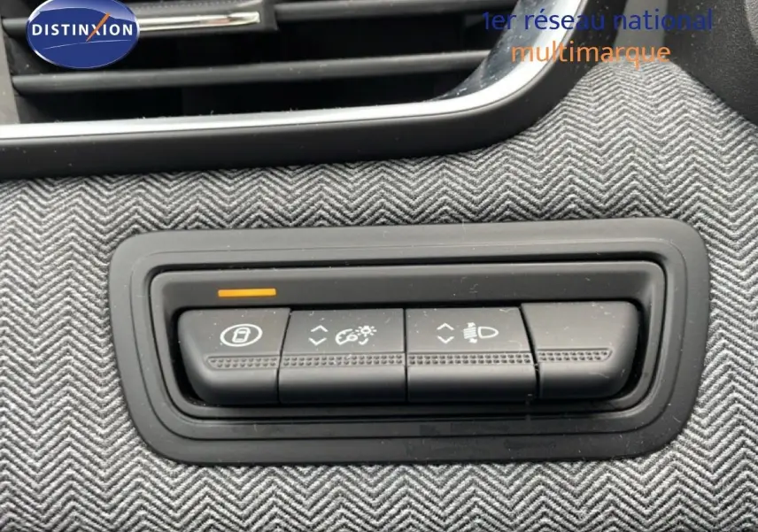 Gros plan sur les commandes d’éclairage et réglages intérieurs de la Renault Clio 2025, tissu gris à chevrons visible.