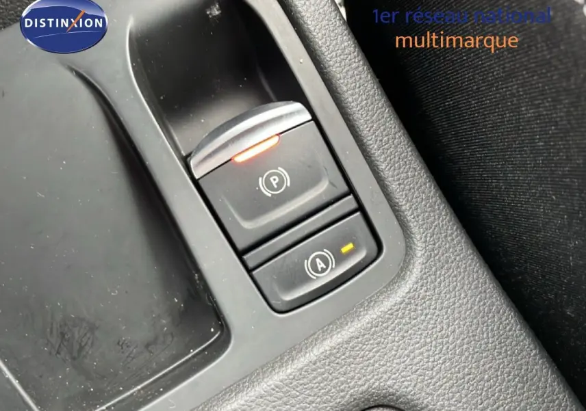 Gros plan sur les commandes de frein à main et arrêt automatique du moteur dans une Renault Clio gris schiste métal, intérieur noir.