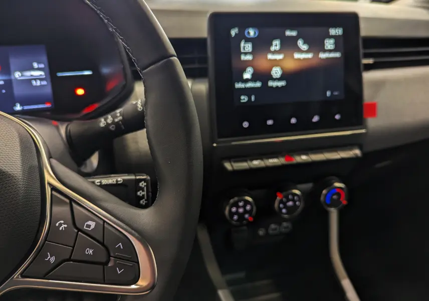 Vue intérieure rapprochée du volant et de l’écran tactile central de la Renault Clio V 2025, finition Evolution, avec commandes au volant visibles.