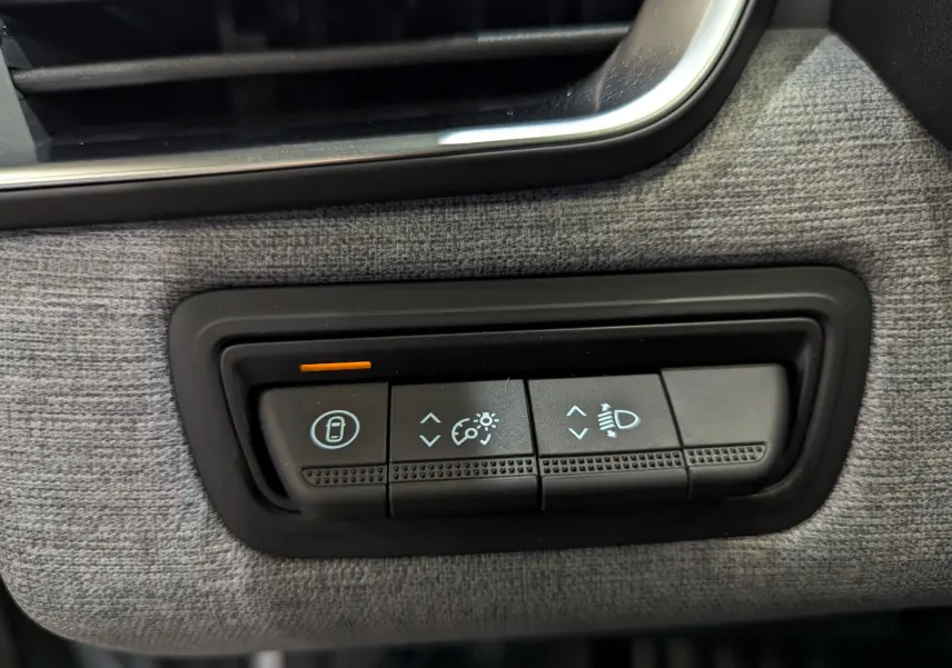 Gros plan sur les commandes de réglage des phares et verrouillage, intérieur tissu gris de la Renault Clio V 2025.