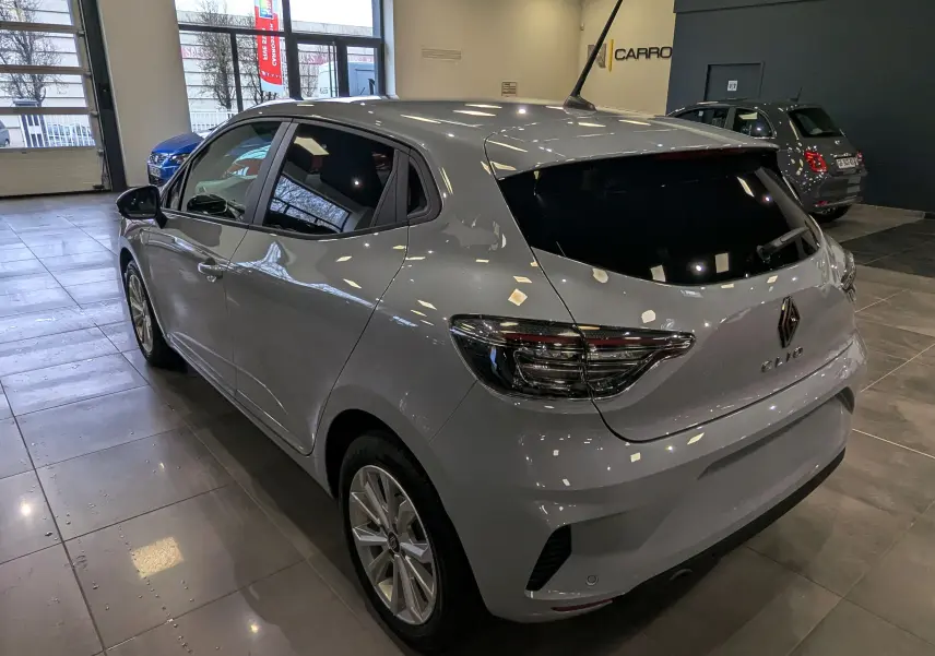 Renault Clio V gris Rafale vue 3/4 arrière droit en intérieur, avec vitres teintées et feux arrière LED distinctifs.