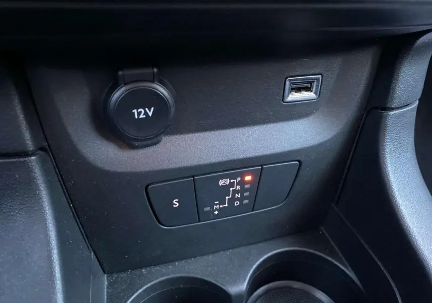 Gros plan sur la commande de boîte automatique et prise 12V dans l’habitacle noir de la Citroën C3 Shine 2023.