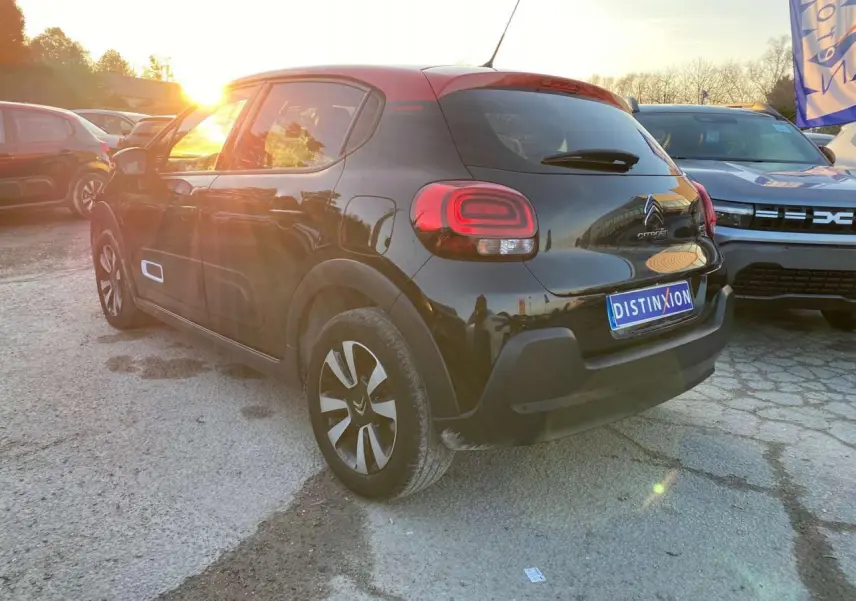 Citroën C3 Shine 2023 noir toit rouge, vue 3/4 arrière droit au coucher de soleil avec jantes alliage diamantées.