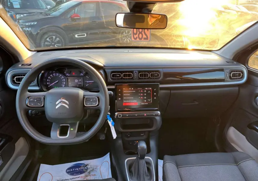 Vue intérieure avant de la Citroën C3 Shine 2023 avec tableau de bord noir et écran tactile central allumé.