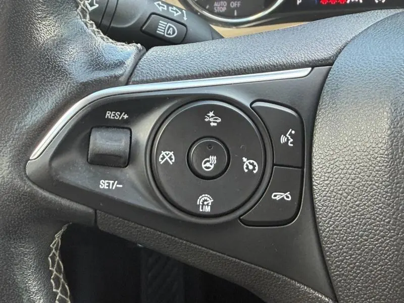 Gros plan sur les commandes multifonctions du volant cuir de l'Opel Insignia Grand Sport, avec réglages de vitesse et assistance.