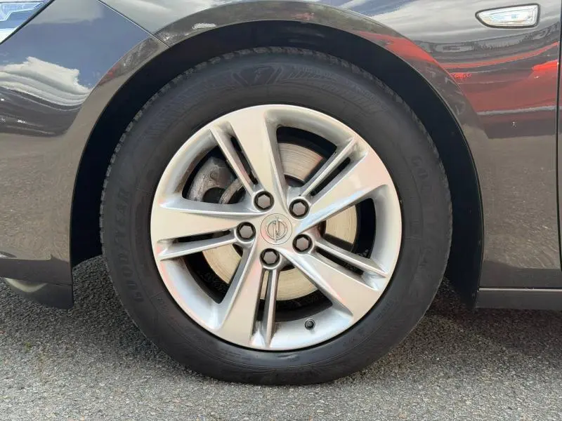 Gros plan sur la roue avant gauche de l’Opel Insignia Grand Sport brun carbone avec jante alu et logo Opel au centre.