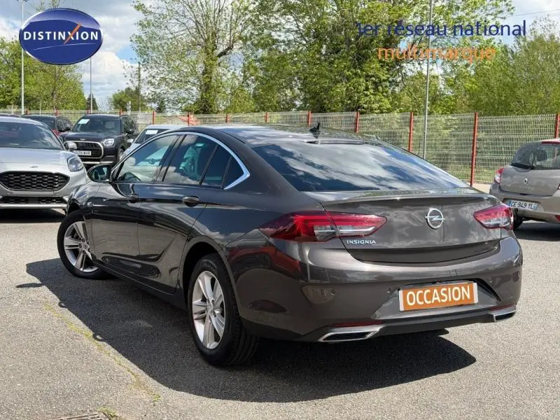 Vue 3/4 arrière droite d'une Opel Insignia Grand Sport brun carbone avec feux LED et double sortie d'échappement chromée.